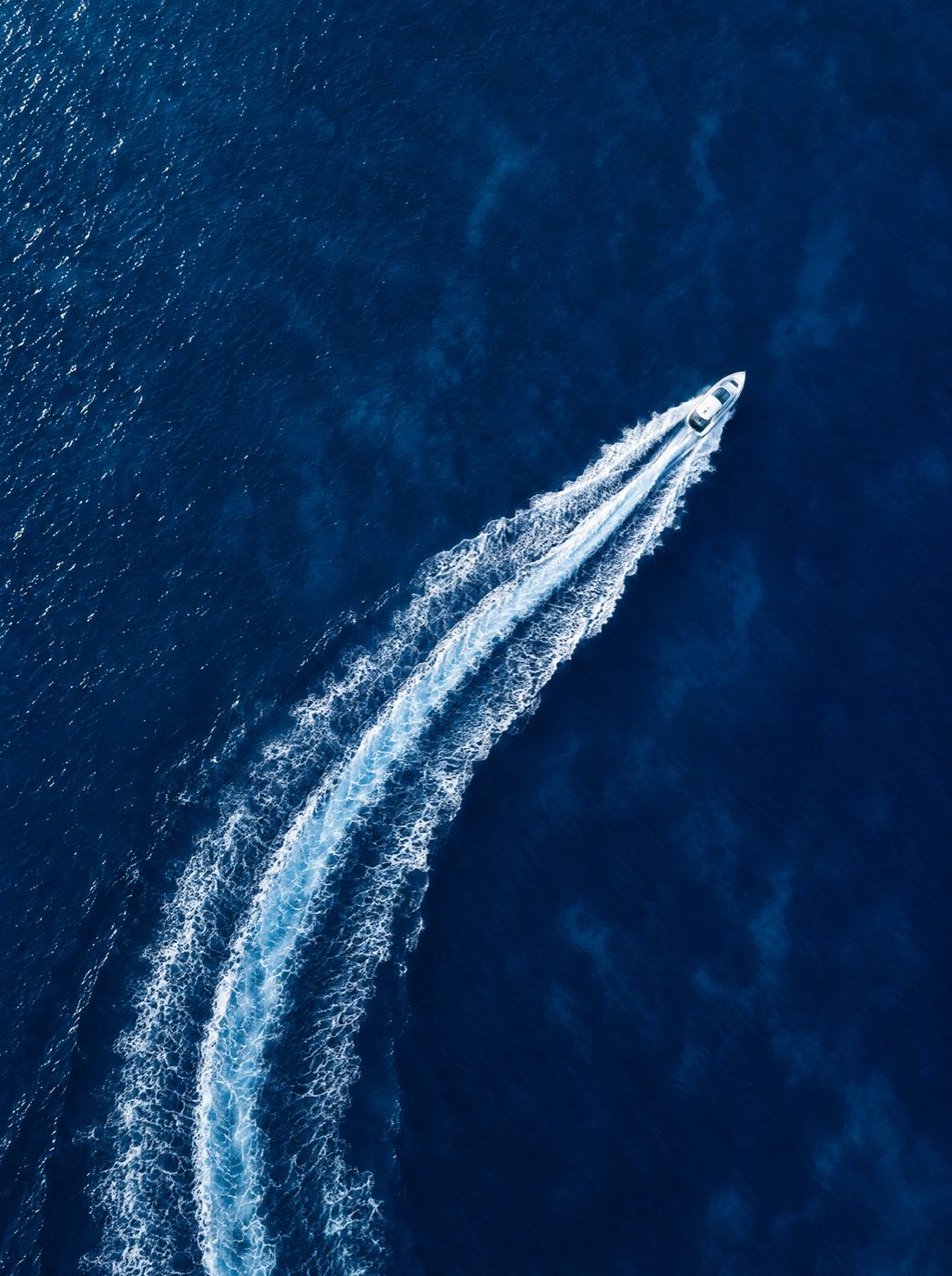 Estela de un bote en aguas azules vista desde el aire